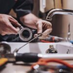Plumber using tools to fix sink in kitchen, close-up on hands, plumbing repair, working